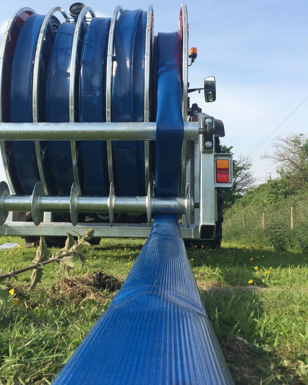 Blue layflat hose running off a hose reel trailer in the paddock